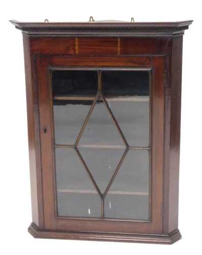 An Edwardian mahogany and boxwood strung hanging corner cupboard, the dentil top raised above an...