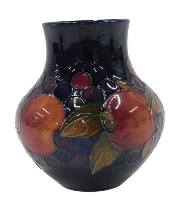 A Moorcroft pottery Pomegranate pattern vase, of compressed bellied circular form, on blue...