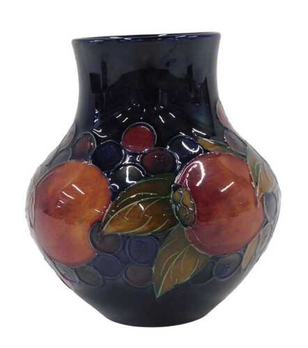 A Moorcroft pottery Pomegranate pattern vase, of compressed bellied circular form, on blue...