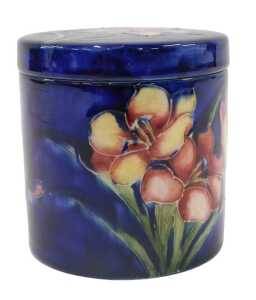 A Moorcroft pottery Freesia pattern jar and cover, of circular form, on blue ground, 11cm high.