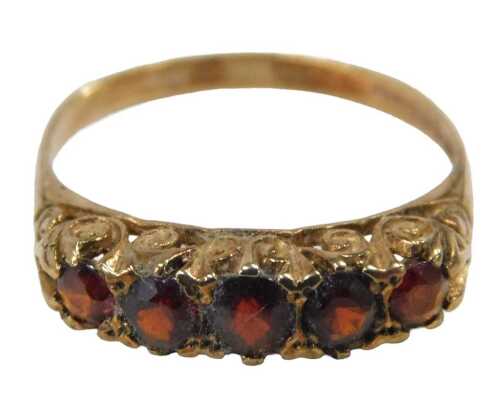 A 9ct gold garnet five stone dress ring, set with five round brilliant cut garnets, each in a...