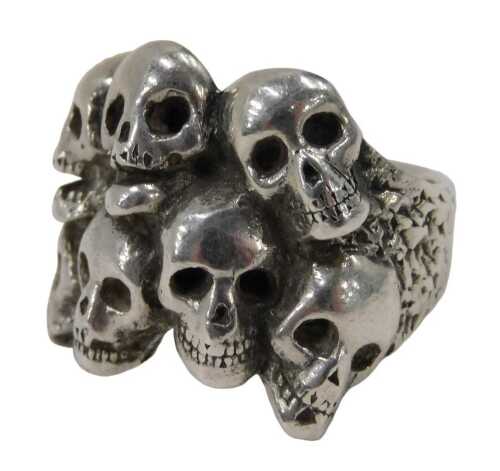 A silver skull ring, mounted with seven skulls, bearing signature, London 1990, ring size P,...