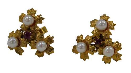 A pair of 9ct gold stud earrings, each formed as three flowers, centred by a garnet and each...