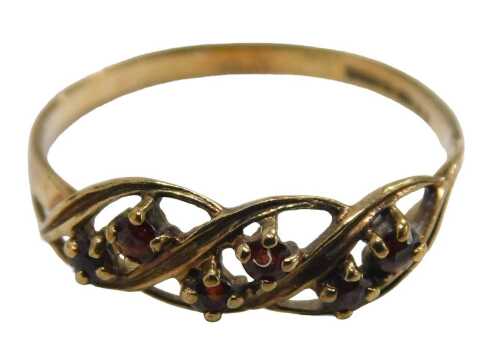A 9ct gold garnet dress ring, the three sectional crossover design, each set with two garnets...