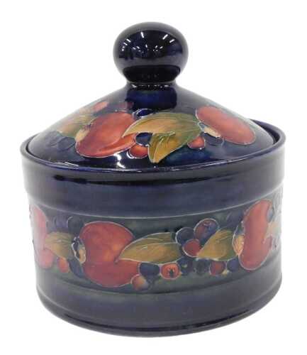 A Moorcroft pottery Pomegranate pattern jar and cover, with circular knop, on blue ground, 15cm...