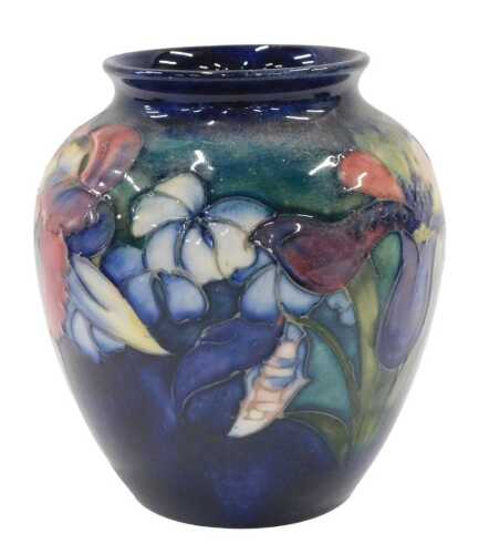 A Moorcroft pottery Orchid pattern vase, of tapering circular form, on blue and green ground,...