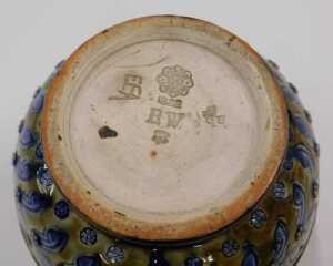 A Doulton stoneware jug, of circular form, with plain spout and raised rosette handle, with a... - 2