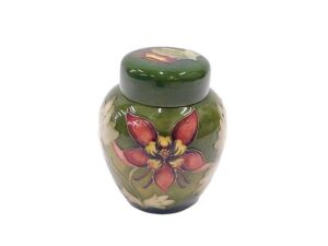 A Moorcroft pottery Columbine pattern ginger jar and cover, of tapering circular form, on green...