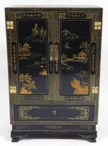A Chinese lacquered cabinet, gilt decorated with river landscapes, having two doors opening to... - 2
