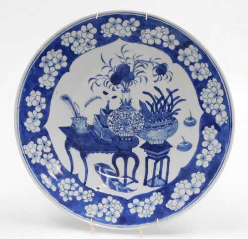 A Chinese Qing Dynasty blue and white porcelain charger, decorated with vases and urns of...