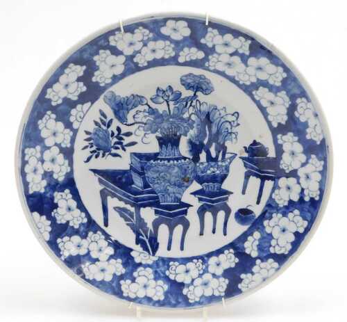 A Chinese Qing Dynasty blue and white porcelain charger, decorated with vases and urns of...