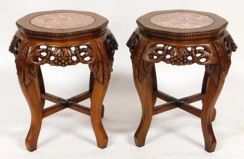 A pair of Chinese hardwood urn stands, the top inset with circular red marble, over fretwork...