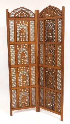 An Eastern hardwood two fold screen, with fretwork paneling and carved decoration of trees in...