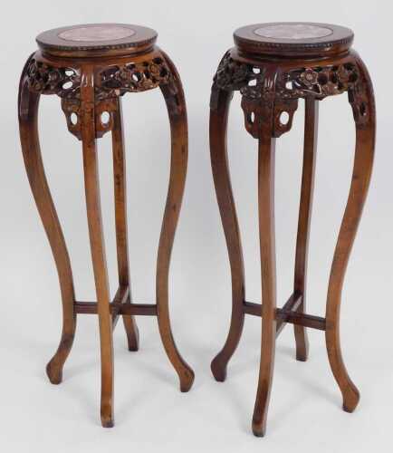 A pair of Chinese hardwood urn stands, the circular top inset with red marble, above a prunus...