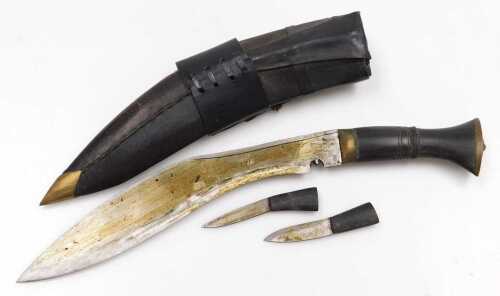A 20thC Gurkha kukri knife, with a brass capped handle, and two additional knives, in a leather...