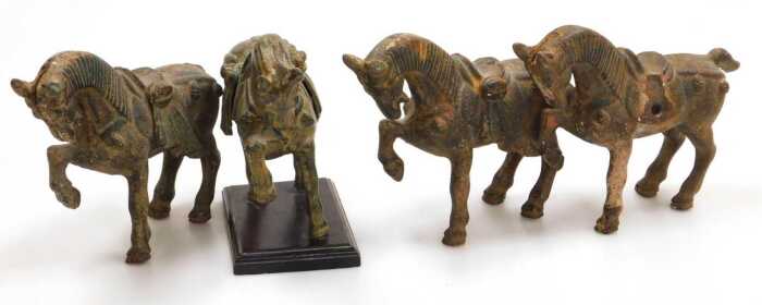 Four Chinese Tang style cast iron figures of war horses, one raised on a wooden plinth, with...