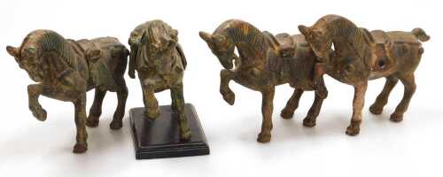 Four Chinese Tang style cast iron figures of war horses, one raised on a wooden plinth, with...