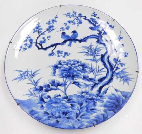 A Japanese Meiji period blue and white porcelain charger, decorated with birds, prunus blossom...