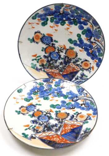 A pair of Japanese Meiji period Imari chargers, decorated with chrysanthemums and pine trees,...