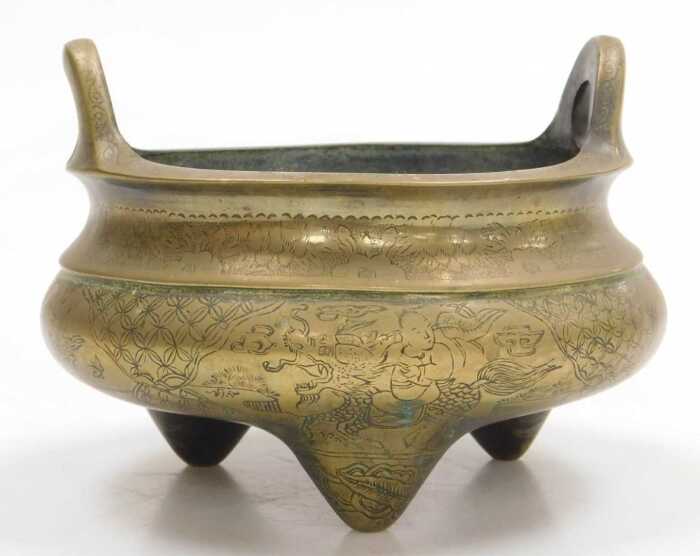 A Chinese bronze tripod censer, engraved with reserves of figures and flowers, apocryphal Xuande...