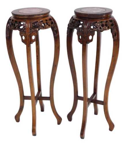 A pair of Chinese hardwood urn stands, the circular top inset with red marble, above a prunus...