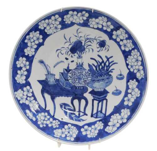 A Chinese Qing Dynasty blue and white porcelain charger, decorated with vases and urns of...