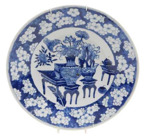 A Chinese Qing Dynasty blue and white porcelain charger, decorated with vases and urns of...