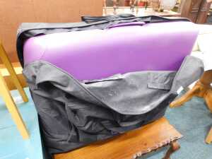 A padded massage table, in a protective zip up carry bag with wheels.
