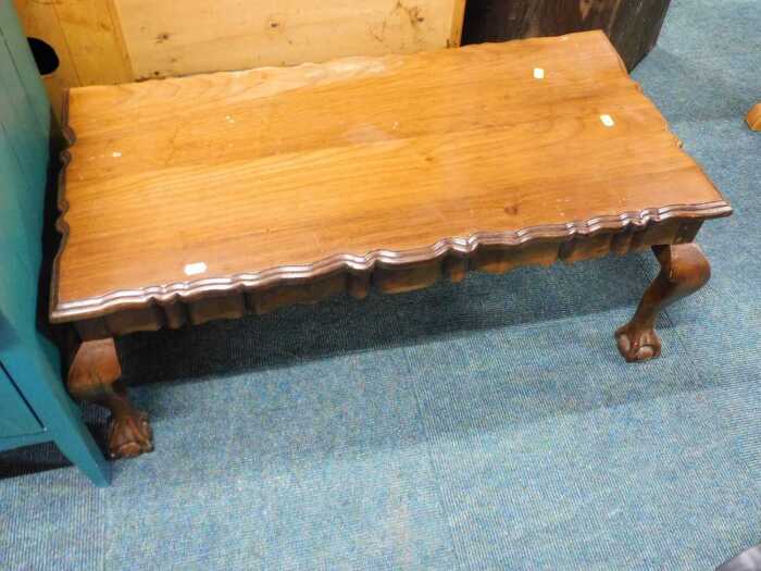 A rectangular wooden coffee table with piecrust edging, serpentine legs and ball and claw feet.