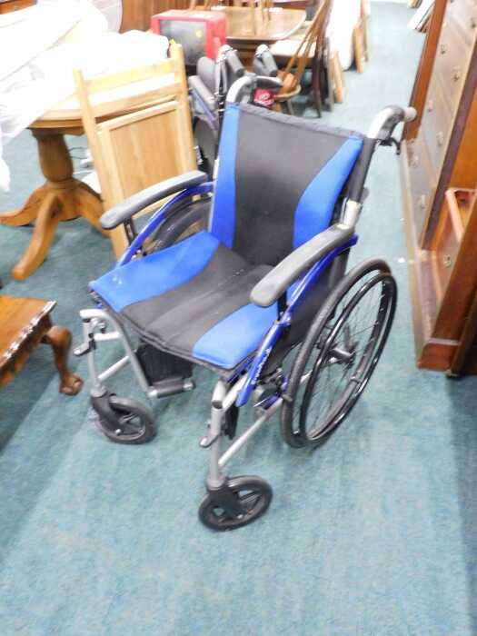 A blue and black wheelchair with fold out foot supports, padded seat and back.