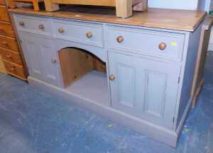 A part painted pine sideboard, with a moulded top, above three drawers and two panelled cabinets...
