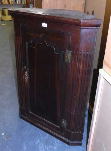 A George III oak hanging corner cabinet, with a moulded top over an arched moulded cabinet door,...