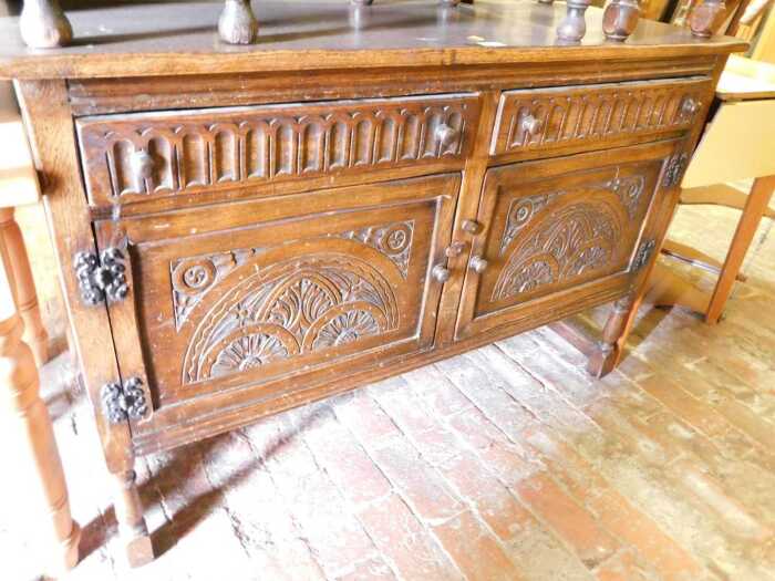 An early 20thC oak sideboard, with two heavily carved drawers above decorative carved panelled...