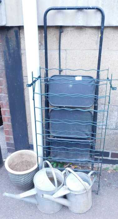 Two galvanised watering cans, a terracotta plant pot, a three tier step ladder, and wire racking....