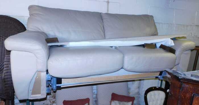 A tooled leather two seater sofa bed, with a mattress.