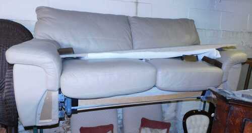 A tooled leather two seater sofa bed, with a mattress.