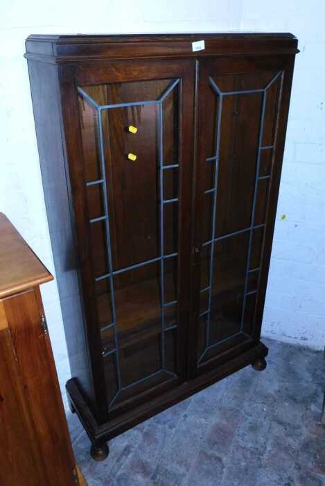 An early 20thC oak display cabinet, the top with a moulded edge above two leaded glazed doors,...
