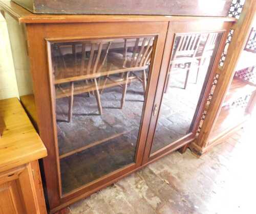 A mahogany display cabinet, the glazed doors enclosing three shelves, raised on tapering legs,...