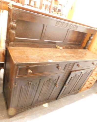 An oak dresser, the top with a raised back above two drawers and two carved cupboards, raised on...