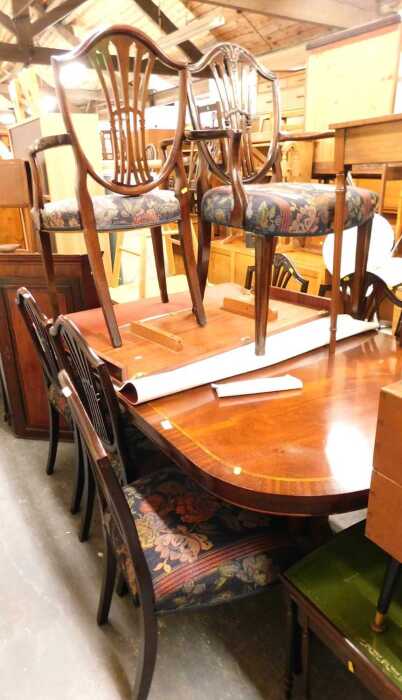 A mahogany and crossbanded extending dining table, raised on twin pedestals with sabre legs,...