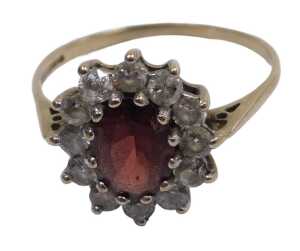 A 9ct gold garnet and cz ring, the oval cut garnet in a surround of brilliant cut czs, in a claw...