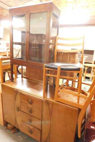 A mid century oak sideboard, the top with a raised back, above four narrow drawers flanked by...