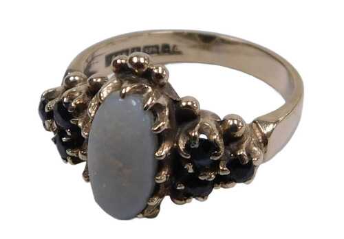 A 9ct gold opal and sapphire ring, the oval opal in a claw setting, with triple sapphire set...