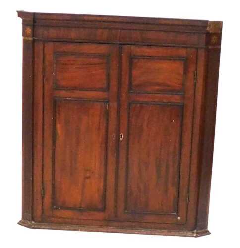 A George III mahogany hanging corner cupboard, the outswept pediment over a pair of doors...