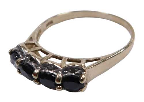 A 9ct gold and sapphire four stone ring, the oval cut stones flanked by tiny czs, in a high claw...