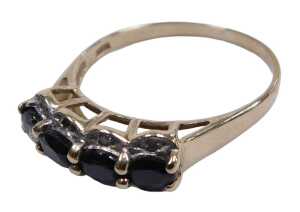 A 9ct gold and sapphire four stone ring, the oval cut stones flanked by tiny czs, in a high claw...