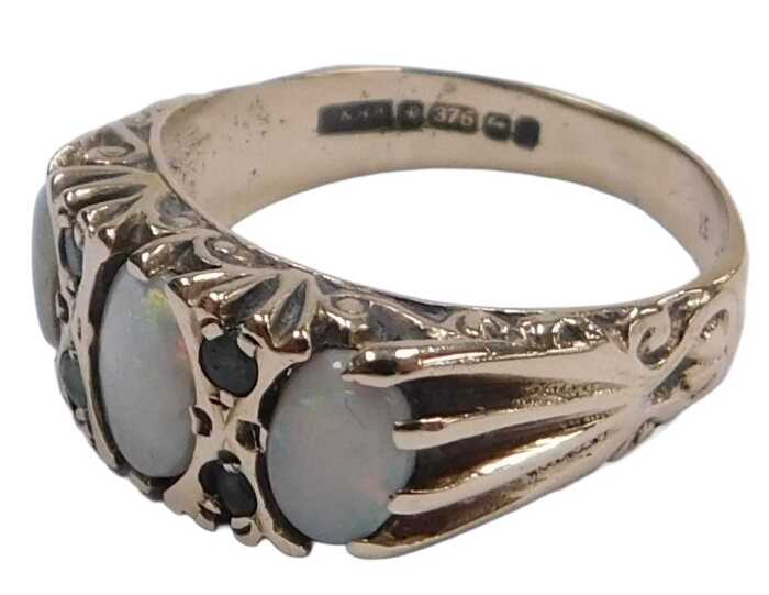 A 9ct gold and opal three stone ring, set with pairs of tiny emeralds at intervals, size O, 3.2g.