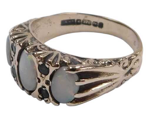 A 9ct gold and opal three stone ring, set with pairs of tiny emeralds at intervals, size O, 3.2g.