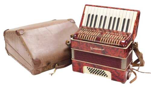 A mid century Worldmaster piano accordion, in a red faux marble case, having thirty-two buttons,...