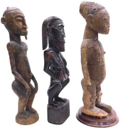 A West African carved fertility figure, modelled squatting, with a baby suckling from her teat,...